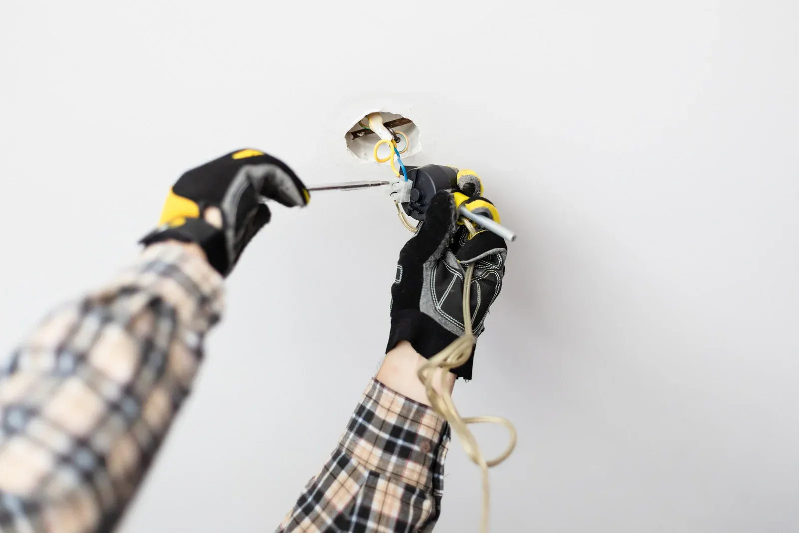 an electrician holding wires an fix broken circuit in a home located in calgary in 2025